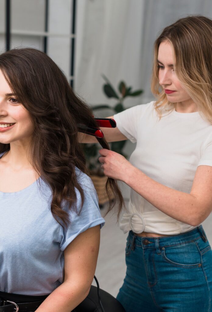 A model receiving a complete beauty makeover with multiple makeup artists working on eyes, lips, and hair.